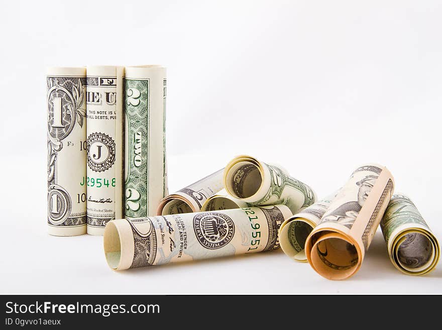 A close up of rolled dollar bills on a white background.