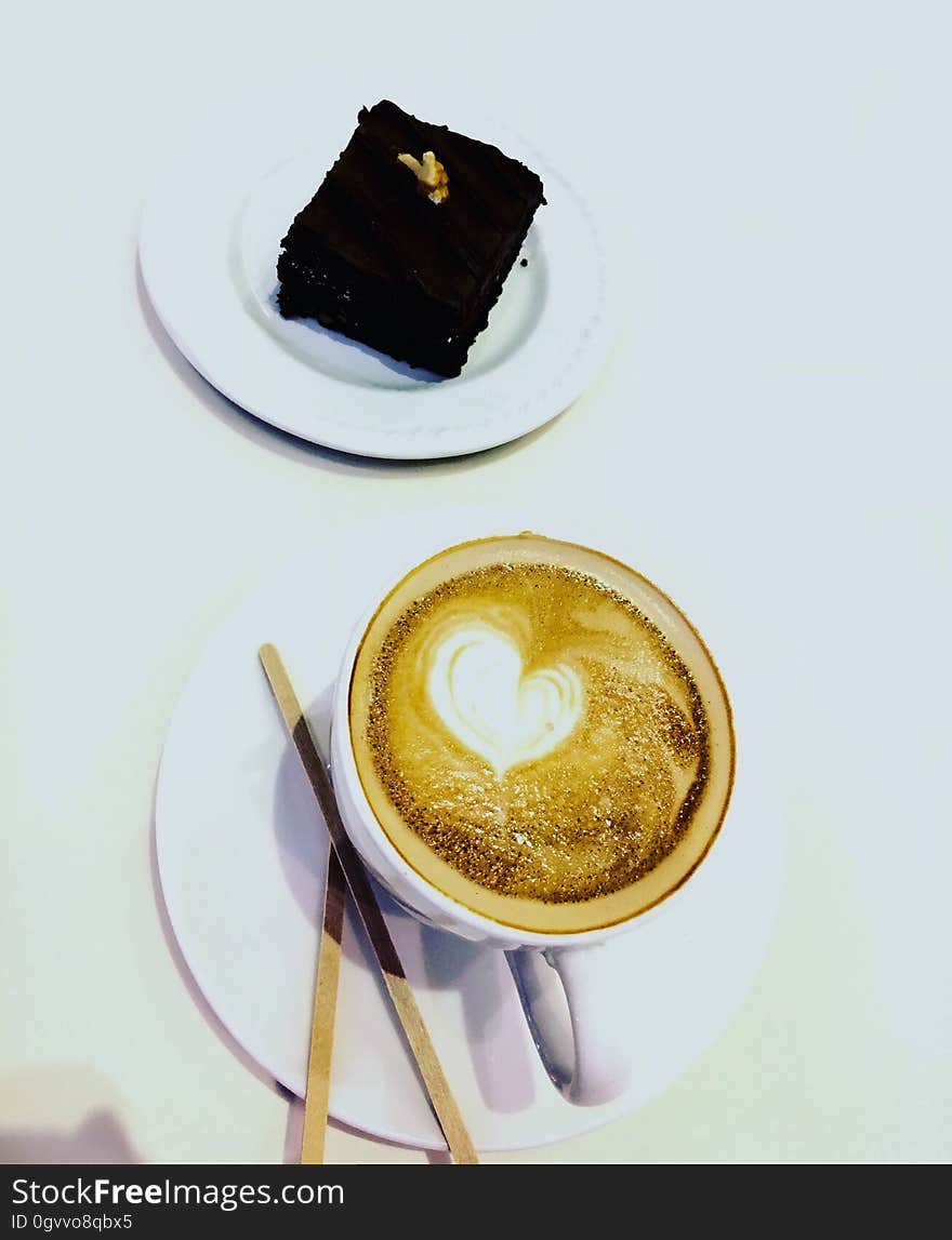 A cup of cappuccino and a piece of chocolate brownie cake. A cup of cappuccino and a piece of chocolate brownie cake.