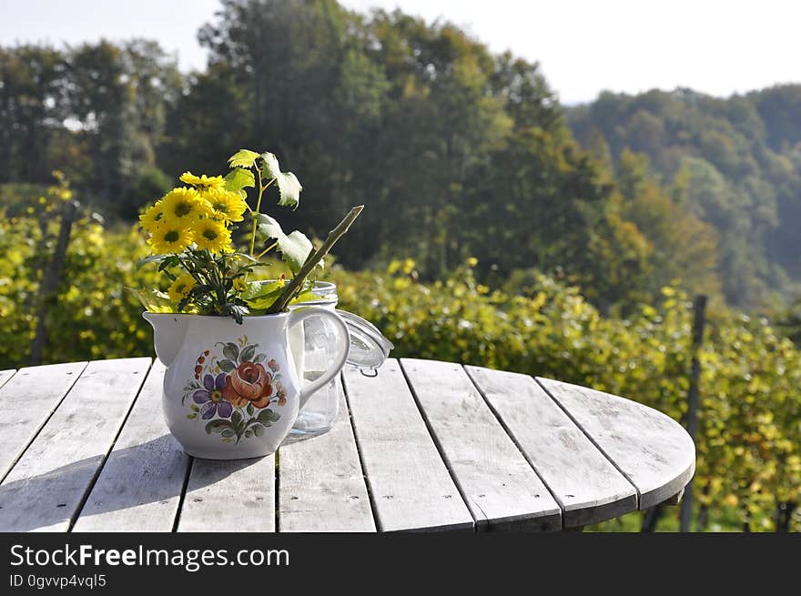 Decorative yellow flowers in a teapot on a wooden table. Decorative yellow flowers in a teapot on a wooden table.