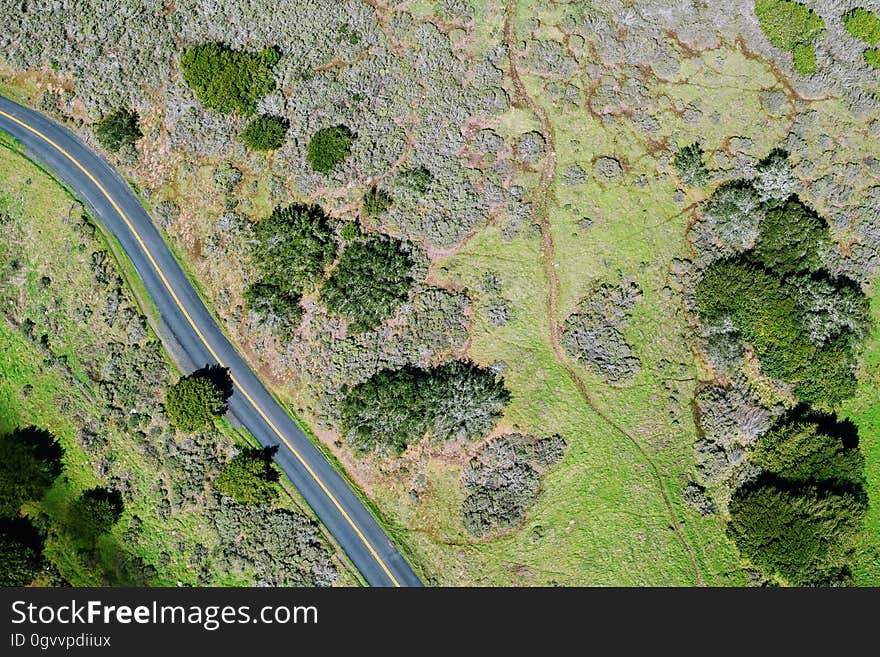 A bird's eye view over a green fields with a road passing through. A bird's eye view over a green fields with a road passing through.