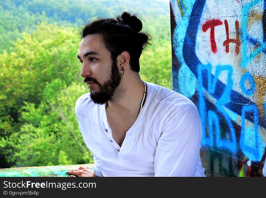 A man sitting in front of a wall with graffiti. A man sitting in front of a wall with graffiti.