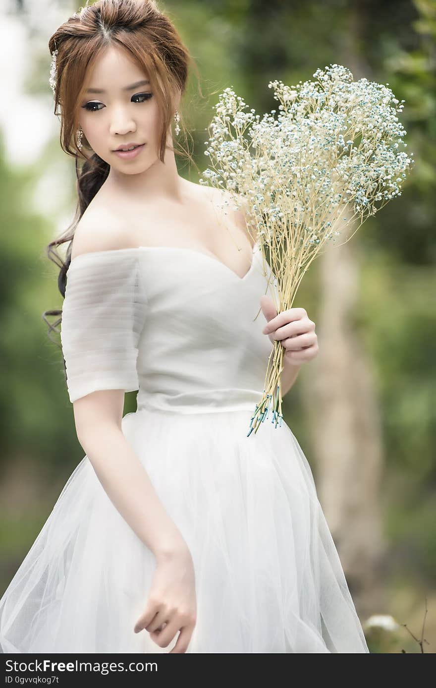 An Asian woman in bridal gown with a bouquet of wild flowers. An Asian woman in bridal gown with a bouquet of wild flowers.