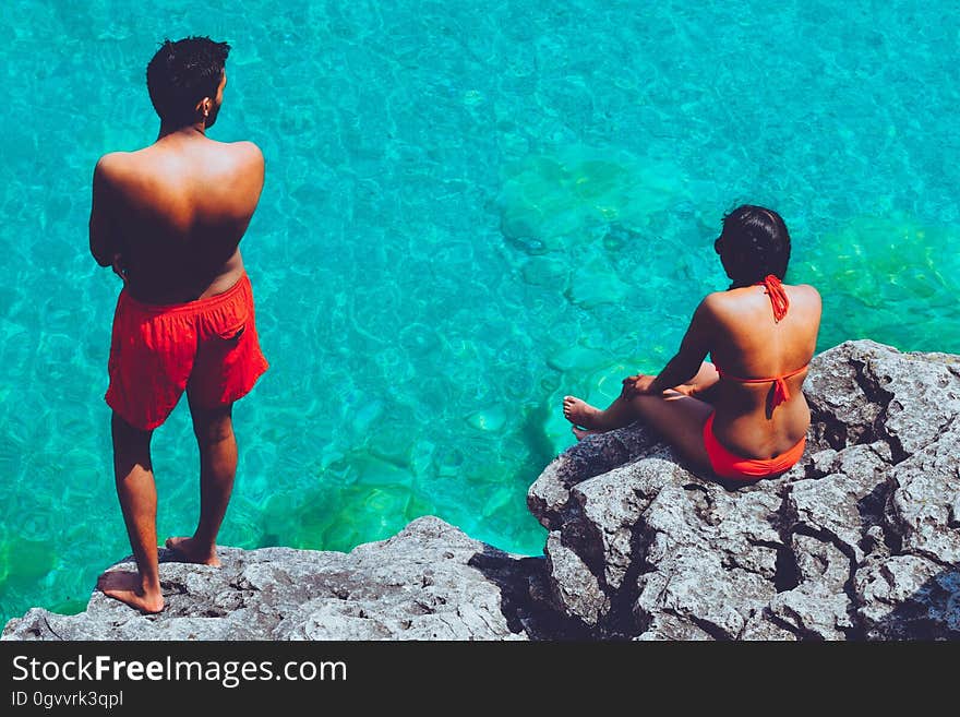 A man and a woman standing on rocks looking at sea. A man and a woman standing on rocks looking at sea.