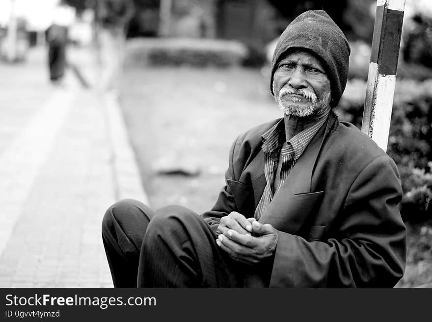 Black and white portrait of sad homeless old man sat in street. Black and white portrait of sad homeless old man sat in street.