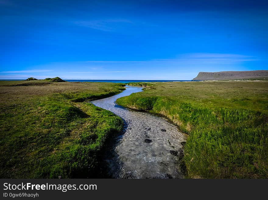 A river leading through green fields to the sea. A river leading through green fields to the sea.