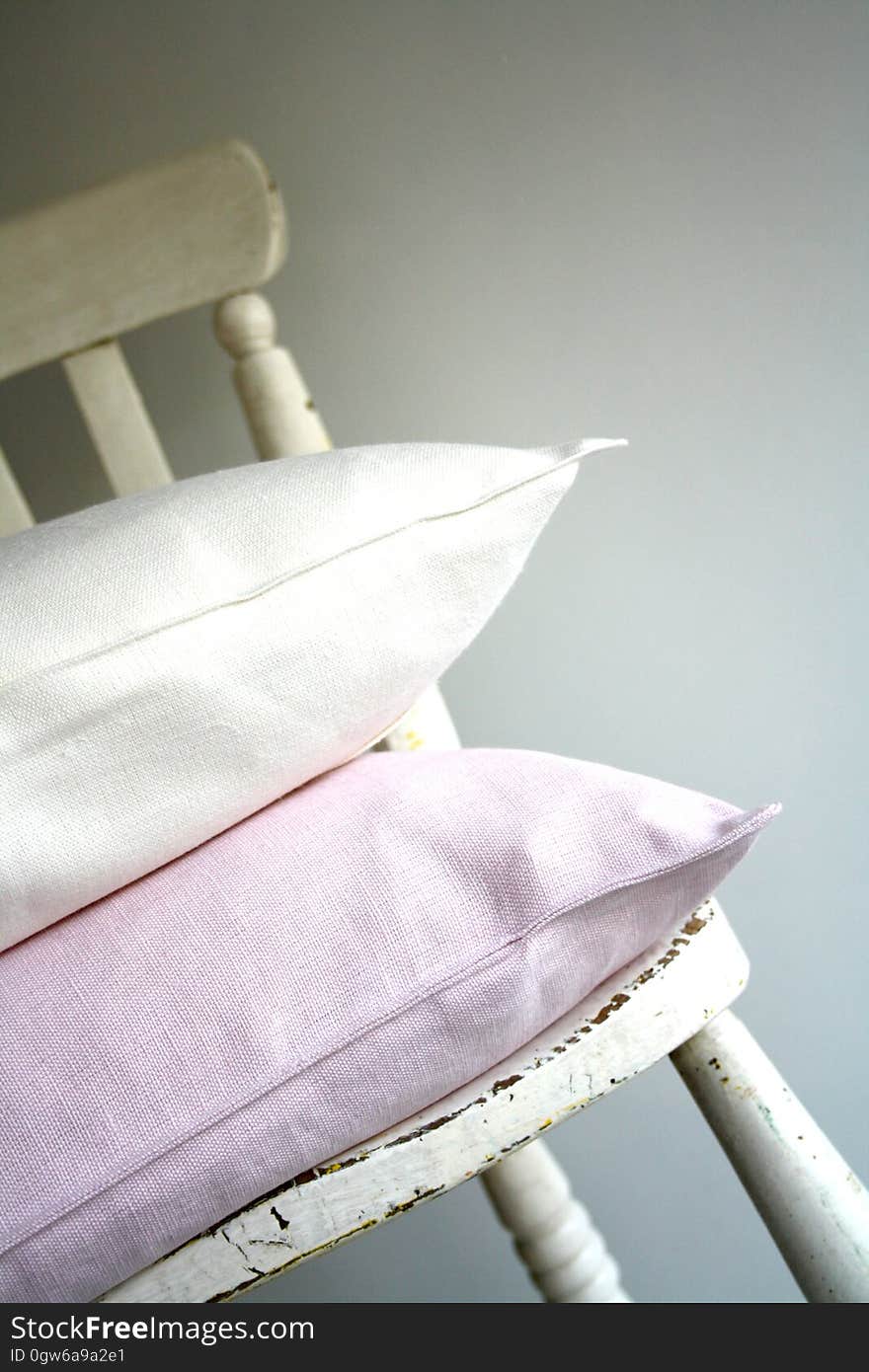 Pink and white pillows on white painted grunge old chair. Pink and white pillows on white painted grunge old chair.