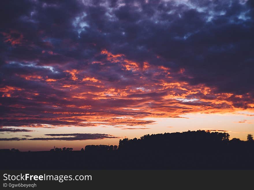 Sun setting in blue skies with silhouette of trees in countryside. Sun setting in blue skies with silhouette of trees in countryside.