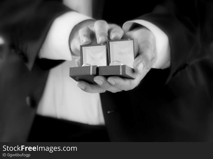 Close up of hands of man in suit holding open jewelry boxes with rings in black and white. Close up of hands of man in suit holding open jewelry boxes with rings in black and white.