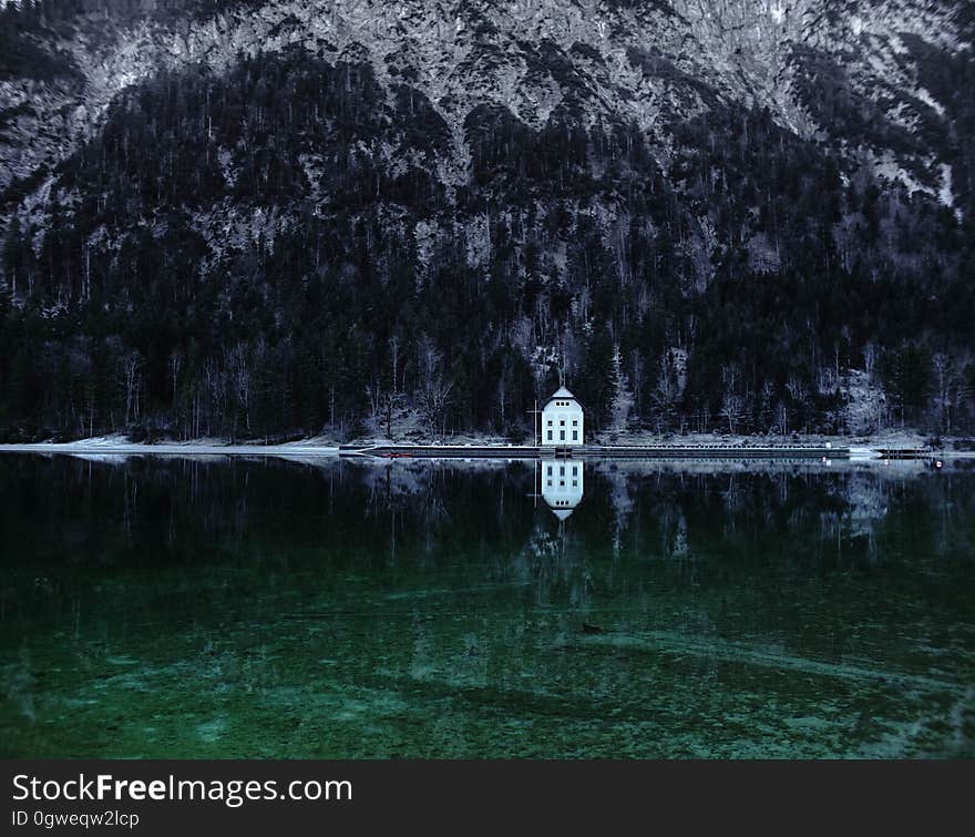 A mountain lake panorama with a house on the shore. A mountain lake panorama with a house on the shore.