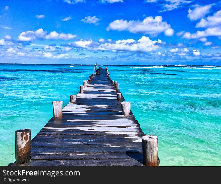 Wooden dock reaching into blue Caribbean waters on sunny day with blue skies. Wooden dock reaching into blue Caribbean waters on sunny day with blue skies.