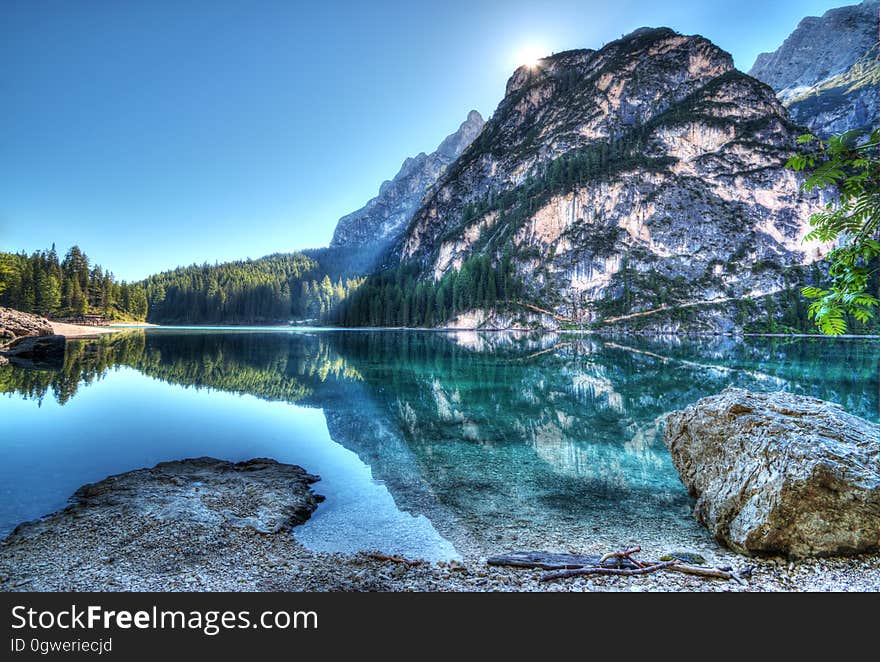 Reflection of rock hillside in clear lake on sunny day with blue skies. Reflection of rock hillside in clear lake on sunny day with blue skies.