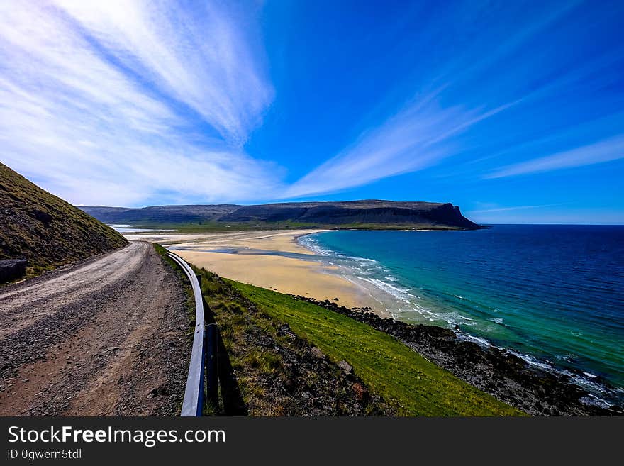 Aerial view of sandy beach along waterfront with blue skies on sunny day.