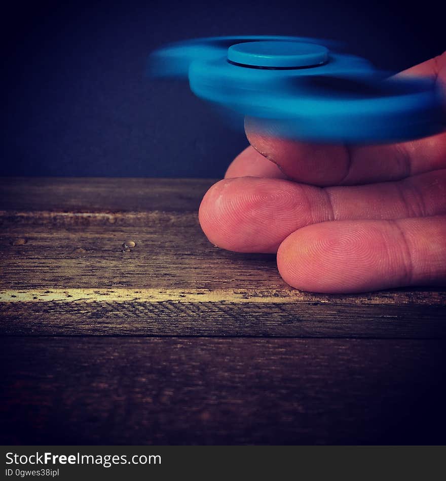 A close up of a hand holding a spinning blue peg top. A close up of a hand holding a spinning blue peg top.