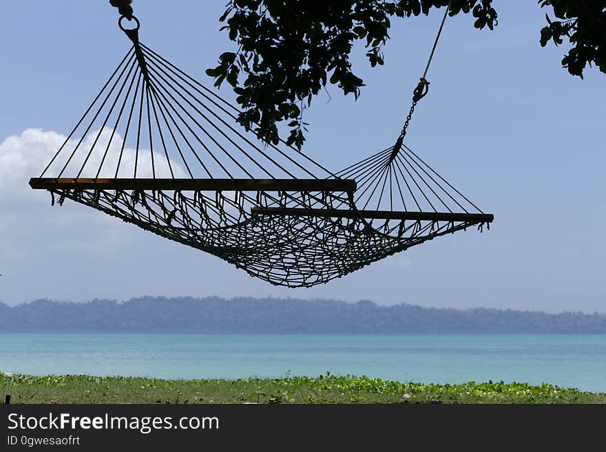 A hammock hanging on a beach and the coast in the background. A hammock hanging on a beach and the coast in the background.