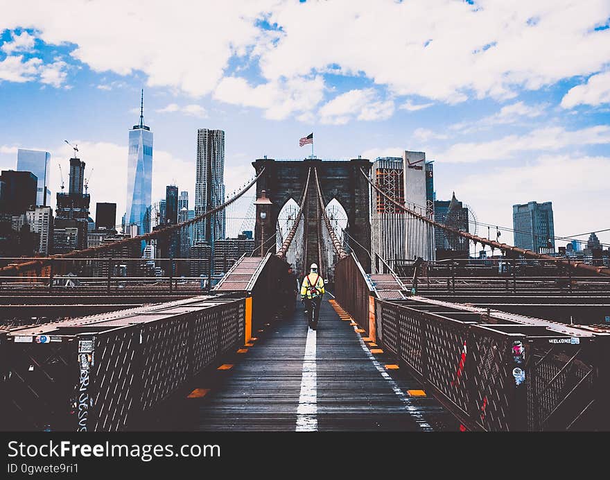 Pedestrian walking across Brooklyn Bridge with skyline of New York City on sunny day. Pedestrian walking across Brooklyn Bridge with skyline of New York City on sunny day.