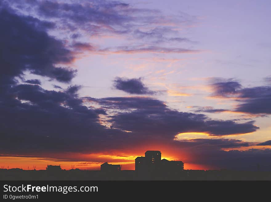 Houses silhouetted against sunset with blue skies.