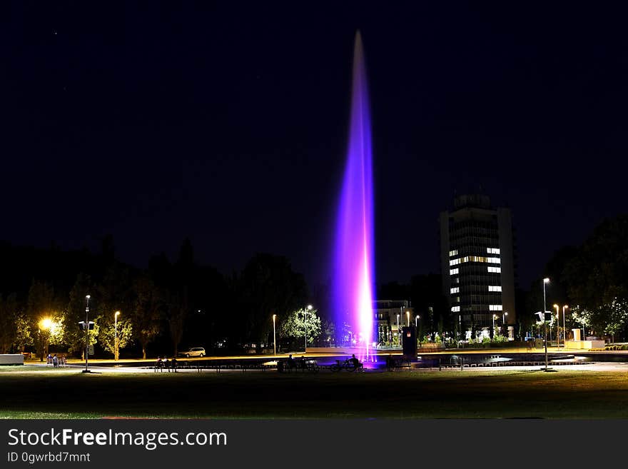 Fountain illuminated in purple lights in city night scene. Fountain illuminated in purple lights in city night scene.