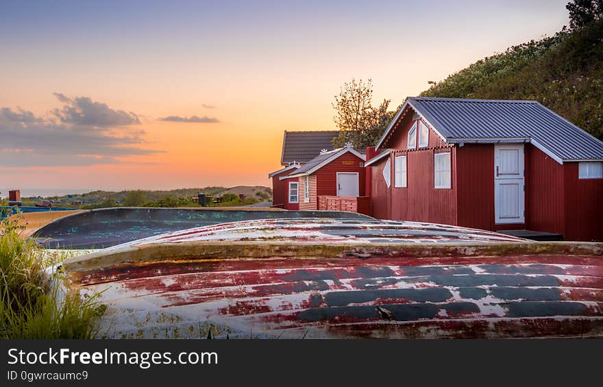 Red rustic houses in field at sunset. Red rustic houses in field at sunset.