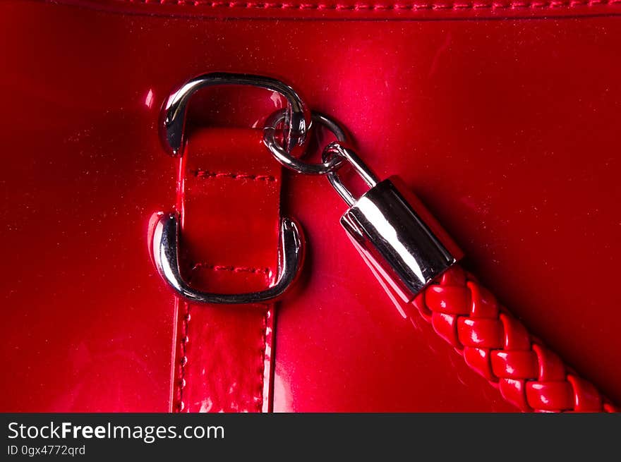 Closeup of the fittings and seams on the red lacquer hand bag. Closeup of the fittings and seams on the red lacquer hand bag