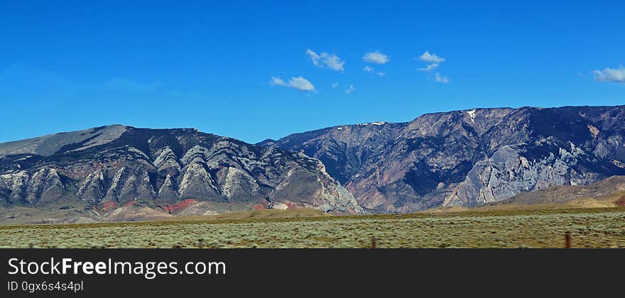 Landscape of mountains over green fields against blue skies on sunny day. Landscape of mountains over green fields against blue skies on sunny day.