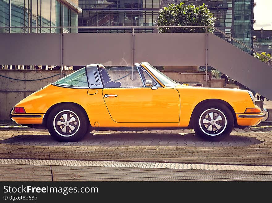 Side view of yellow Porsche 911 AG motor car parked on sidewalk in city. Side view of yellow Porsche 911 AG motor car parked on sidewalk in city.