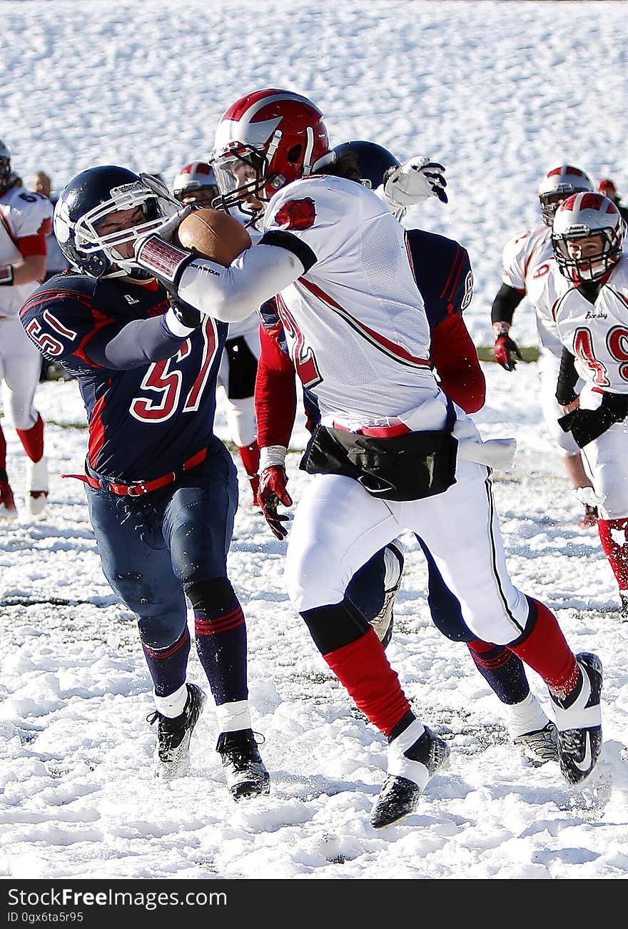 Football players during game being played on snowy field on sunny day. Football players during game being played on snowy field on sunny day.