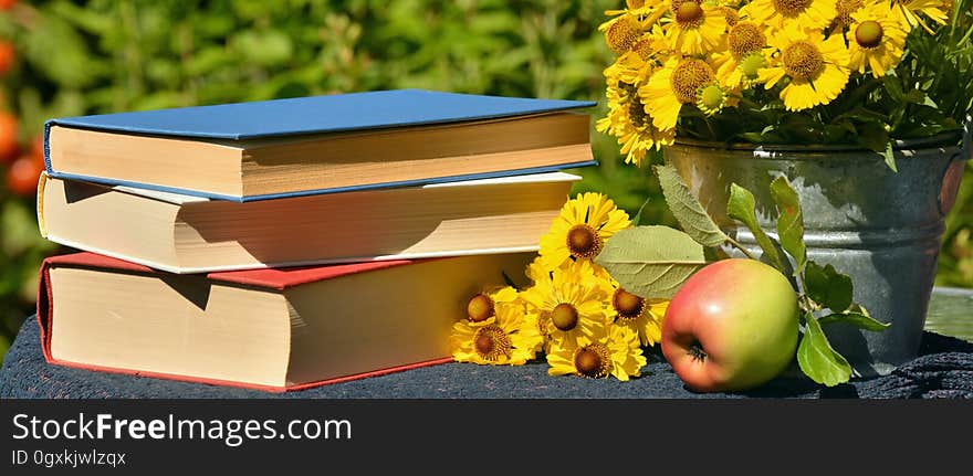 A stack of books on a table with an apple. A stack of books on a table with an apple.