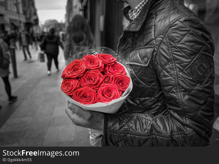 A man in a jacket holding a red rose bouquet. A man in a jacket holding a red rose bouquet.