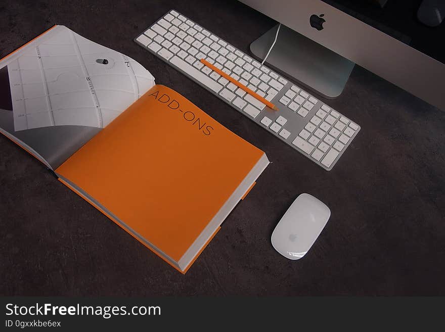 Orange Book in Distance With Silver Imac