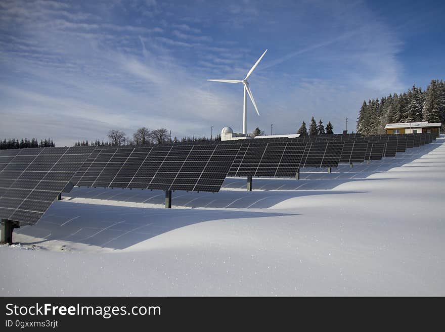 Snowy landscape with solar power panels and wind turbine on sunny day. Snowy landscape with solar power panels and wind turbine on sunny day.