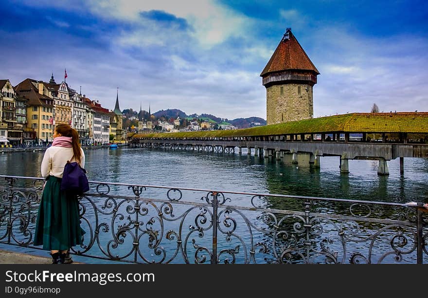 Woman standing on railing by lake in Switzerland on sunny day. Woman standing on railing by lake in Switzerland on sunny day.