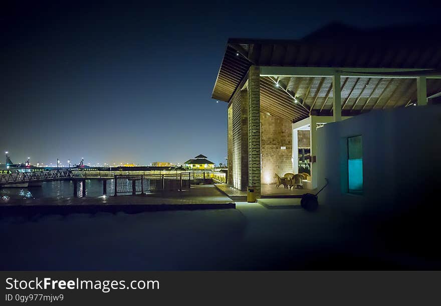 House on waterfront illuminated at night with city skyline in background. House on waterfront illuminated at night with city skyline in background.