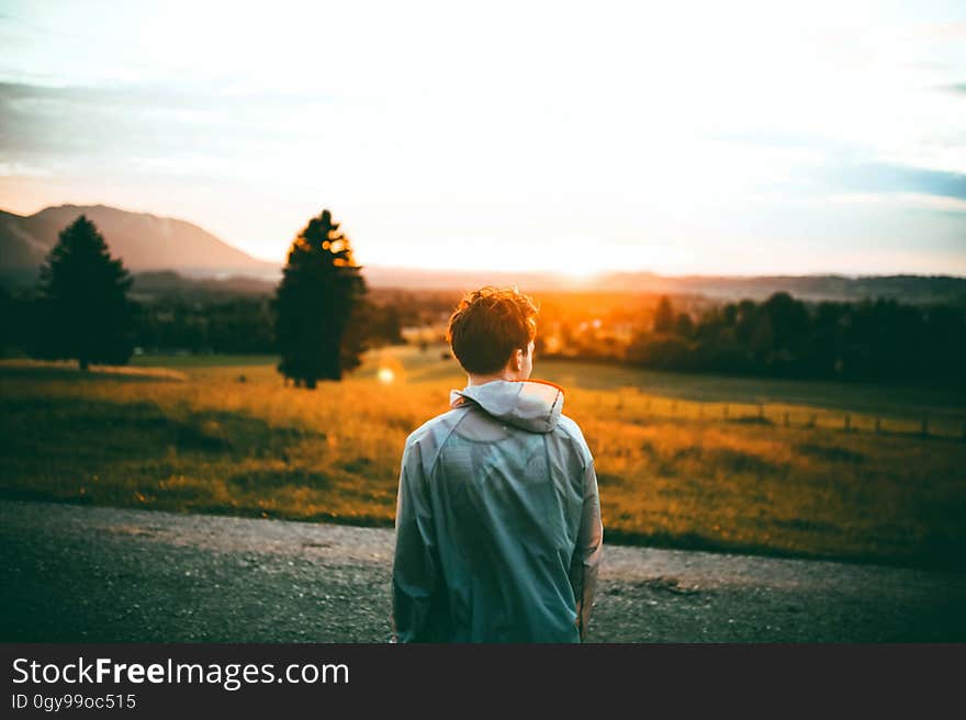 A boy outdoors watching the sunset.