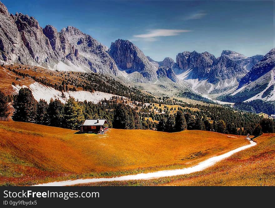 Road (track) to the forest and high snow covered mountain range with a single dwelling (house) on the hillside. Road (track) to the forest and high snow covered mountain range with a single dwelling (house) on the hillside.