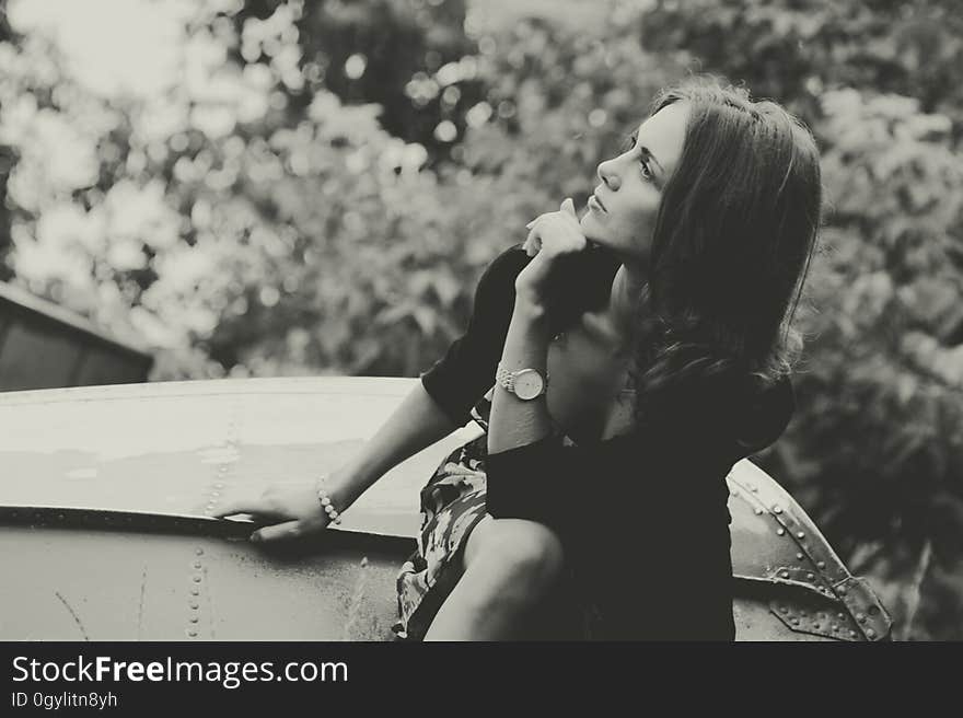 Black and white view of thoughtful woman sat outdoors looking to side,