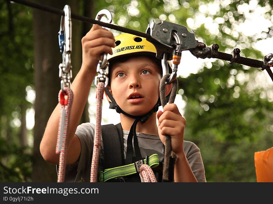 A boy fixing a cable on a zipline. A boy fixing a cable on a zipline.