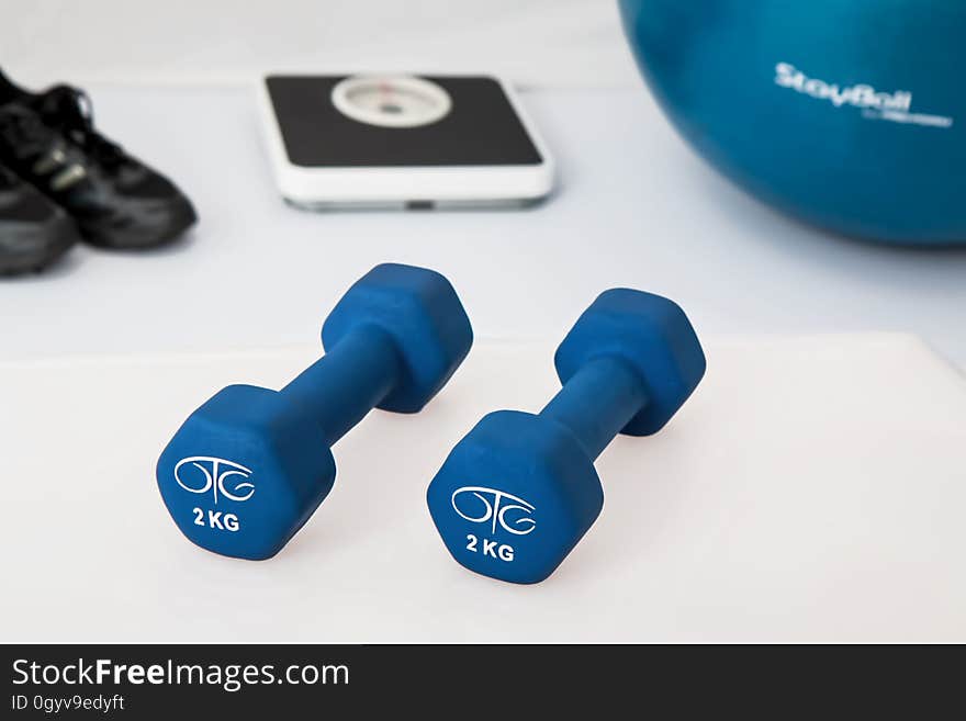 Exercise weights and ball on floor with scale and black shoes. Exercise weights and ball on floor with scale and black shoes.