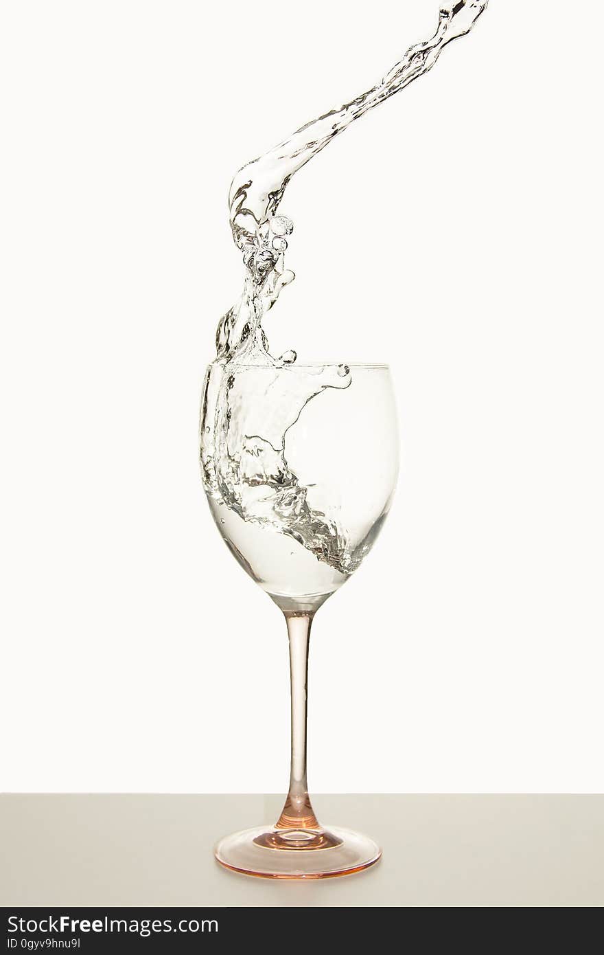 Crystal wine glass with white wine splashing into goblet. Crystal wine glass with white wine splashing into goblet.