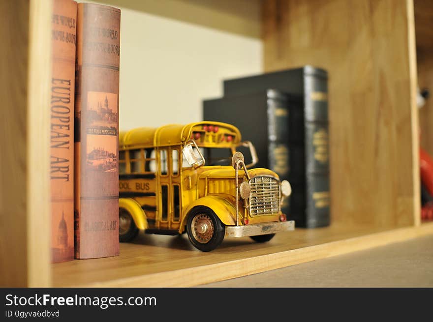 A yellow toy school bus in a bookshelf. A yellow toy school bus in a bookshelf.