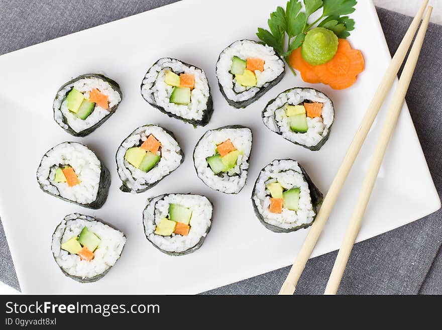 A plate with maki sushi, wasabi and chopsticks. A plate with maki sushi, wasabi and chopsticks.