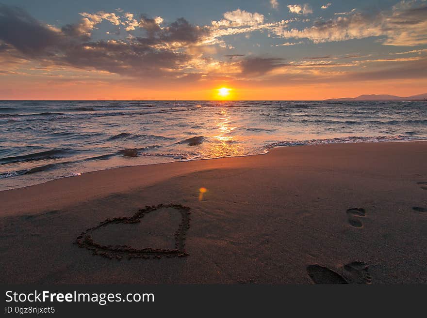 A heart drawn in the sand on the beach at sunset. A heart drawn in the sand on the beach at sunset.