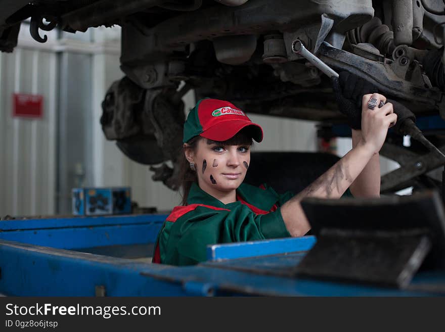 Female automotive mechanic working on car in garage.