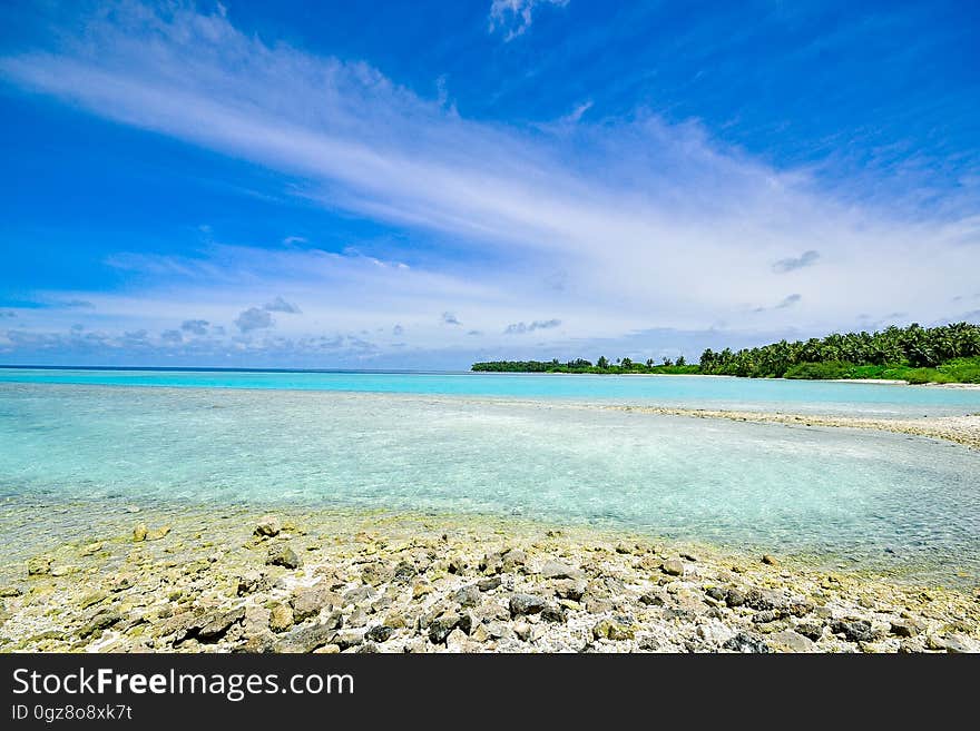 Sandy beach along coastline of blue waters with blue skies on sunny day. Sandy beach along coastline of blue waters with blue skies on sunny day.