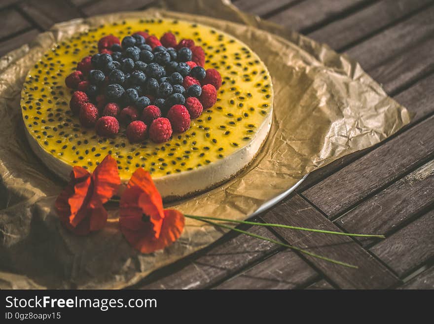 Close up of whole basil seed cheesecake topped with fresh raspberries and blueberries on rustic wooden table. Close up of whole basil seed cheesecake topped with fresh raspberries and blueberries on rustic wooden table.