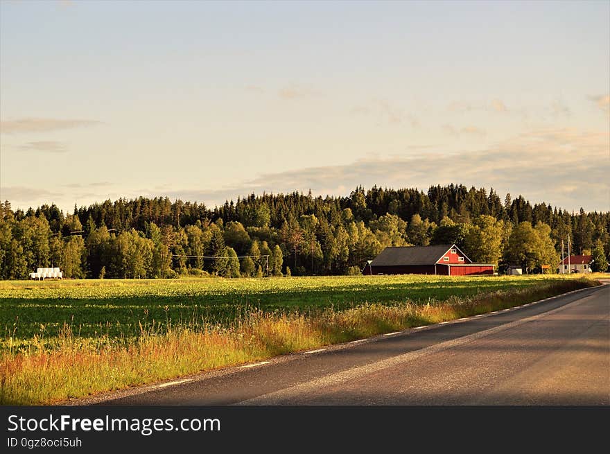 A farmhouse and fields next to a road. A farmhouse and fields next to a road.