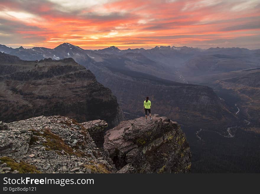 A hiker standing on a rock on a mountain top. A hiker standing on a rock on a mountain top.