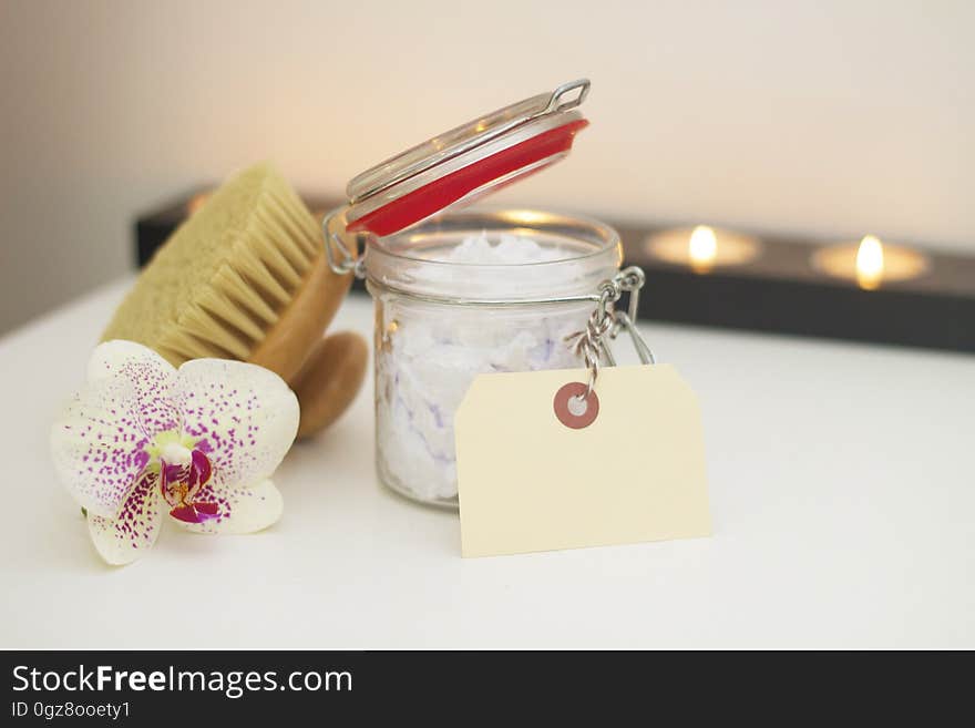 A jar of bath salt with a brush and orchid flower. A jar of bath salt with a brush and orchid flower.