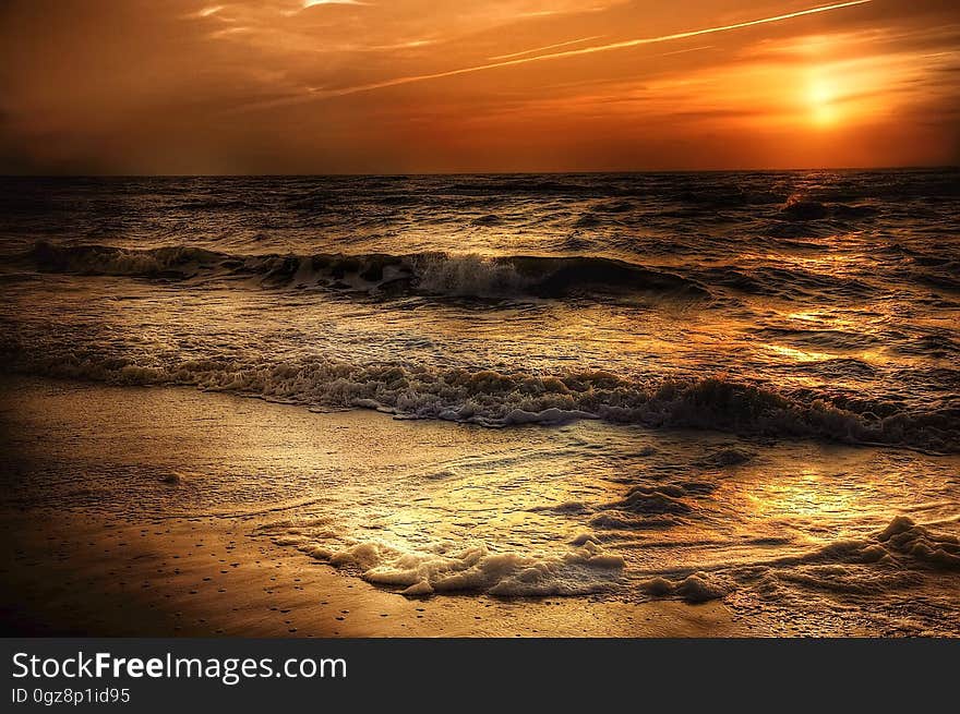 A beautiful coastal sunset with waves crashing on the shore.