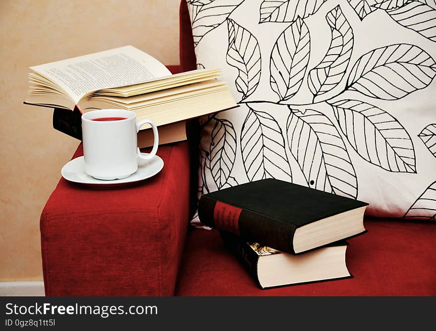 Closed and open books on armchair with cup of coffee. Closed and open books on armchair with cup of coffee.