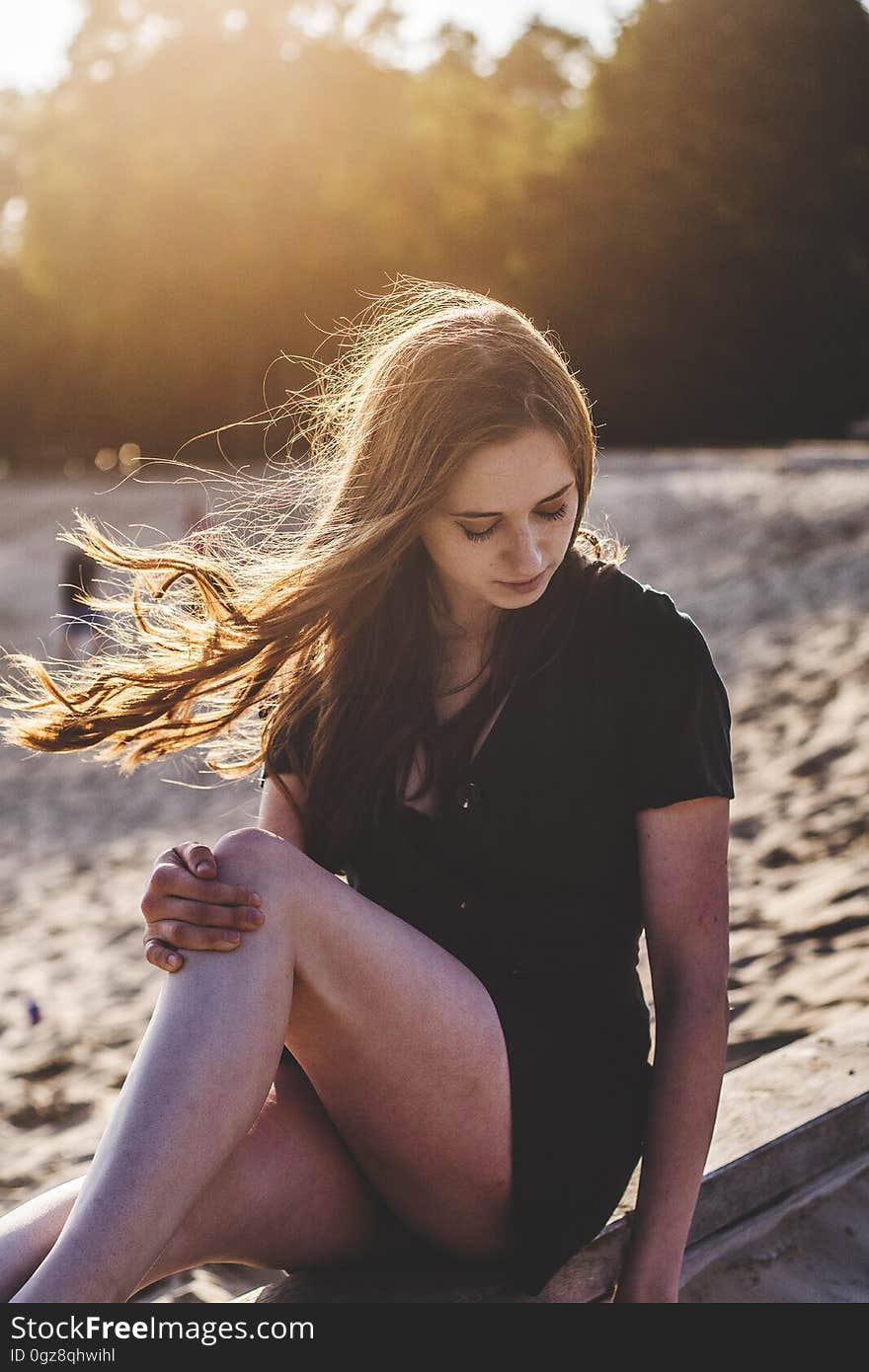 Profile portrait of pretty woman sitting on wooden boardwalk railing next to beach on sunny day. Profile portrait of pretty woman sitting on wooden boardwalk railing next to beach on sunny day.